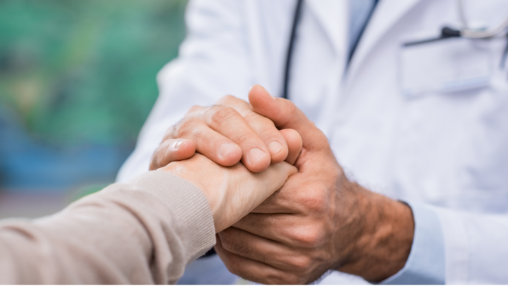 Close up of doctor hand reassuring her female patient at hospital. Closeup hands of medical doctor carefully holding patient's hands. Kind doctor giving real support for patient.