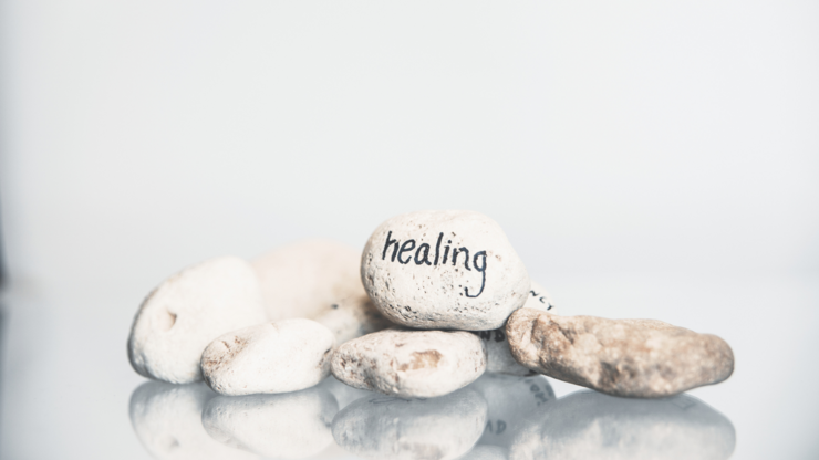 White pebble with the word 'healing' written on it with a black permanent marker.