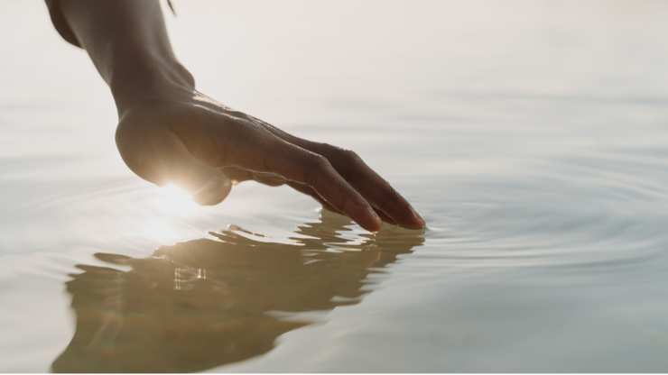 A person's hand touching the surface of water