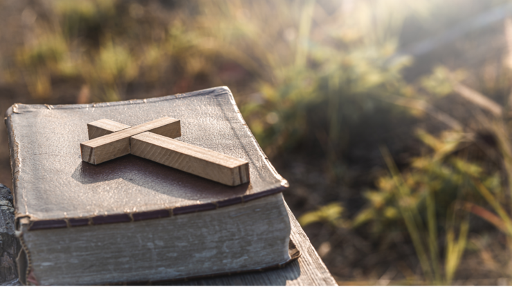 The Cross with old Bible lay on wooden plate, christian concept.