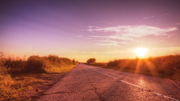 Beautiful purple countryside road with sunset. Lens flare (not Photoshop added).Toned HDR image