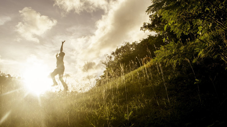 man in sunrise arms up