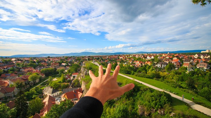 Human Hand Under White and Blue Sky on Green Grass Field